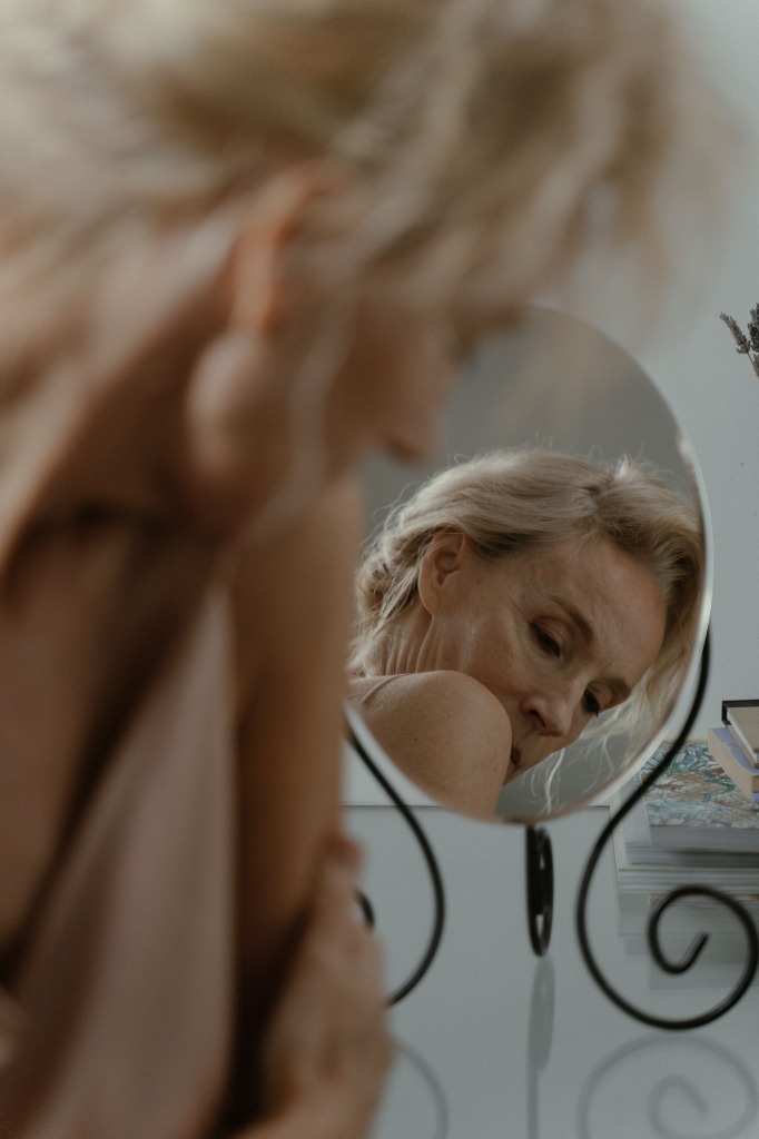 Starija plava žena gleda se u ogledalu